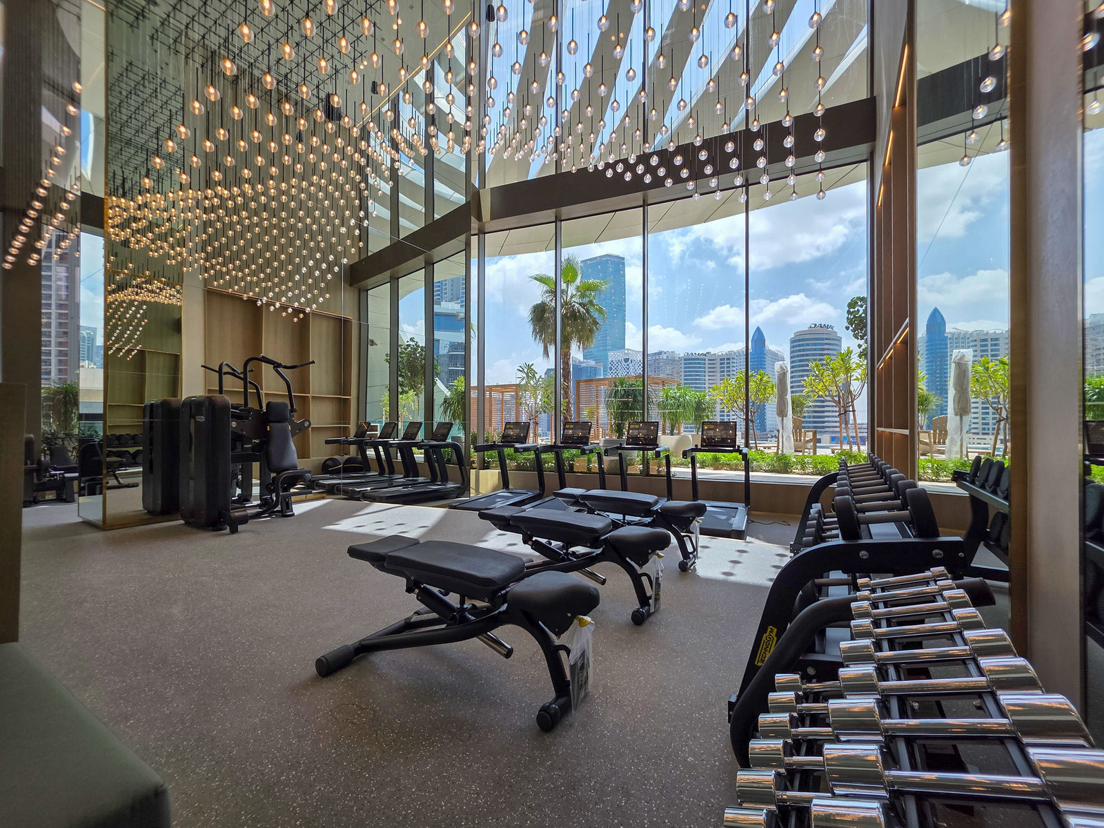 Residential building gym with cardio and strength equipment and floor-to-ceiling windows